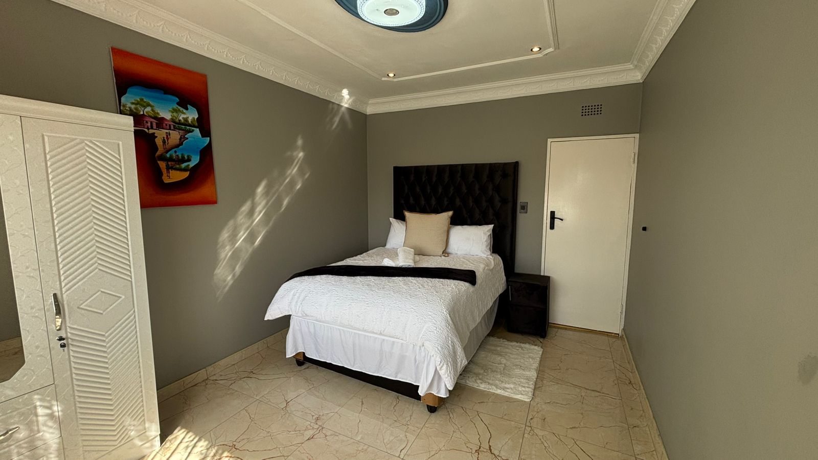 Sunlit bedroom with white bedding and gray walls