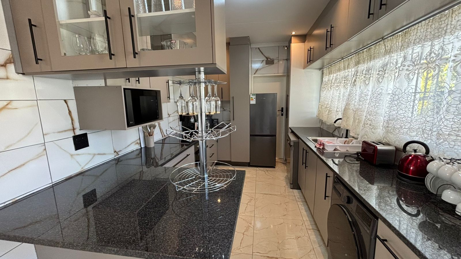 Kitchen counter with glass rack, appliances, and refrigerator